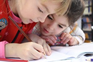 Two Kids Writing on a Notebook